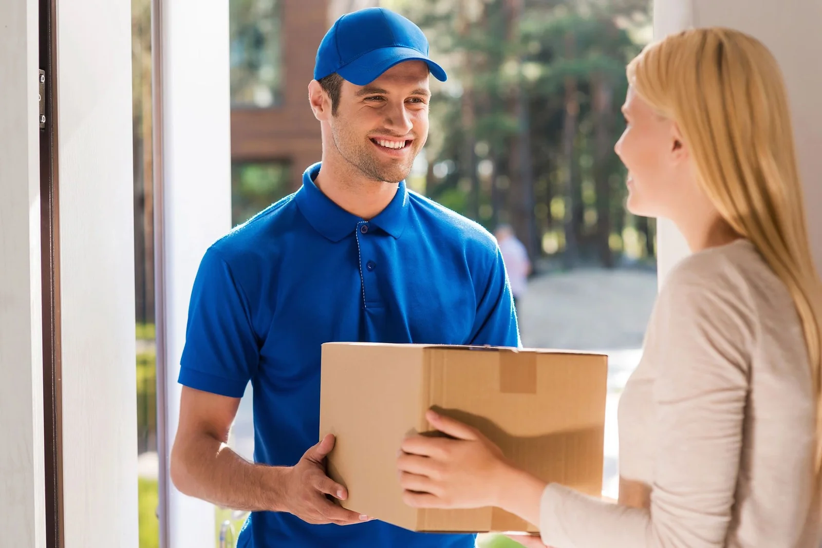 Mover handing a carton to a customer at the front door of a house