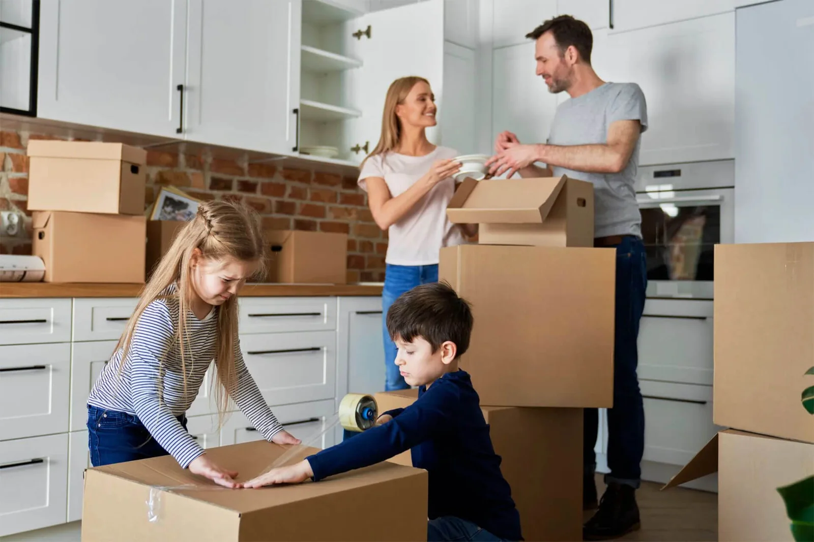 Family packing kitchenware into cartons before a house move
